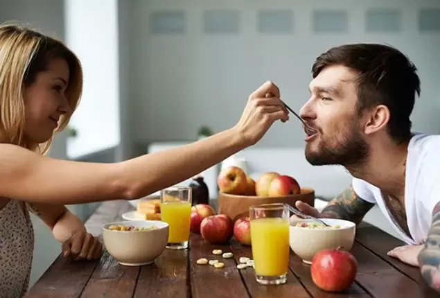 една жена храни мъж с ядки за повишаване на потентността